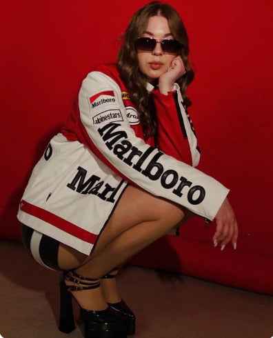 Marlboro Racing Jacket – Embrace Vintage Motorsport Style and Heritage by Xoratic, white embroidered jacket worn with sunglasses against a red background