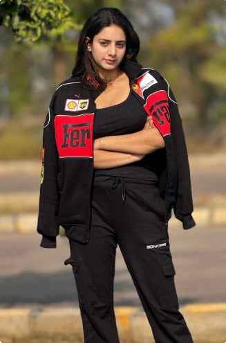 Ferrari Racing Jacket in Black - Embrace the Spirit of Motorsport worn by a woman with red racing details and black athletic pants outdoors by Xoratic