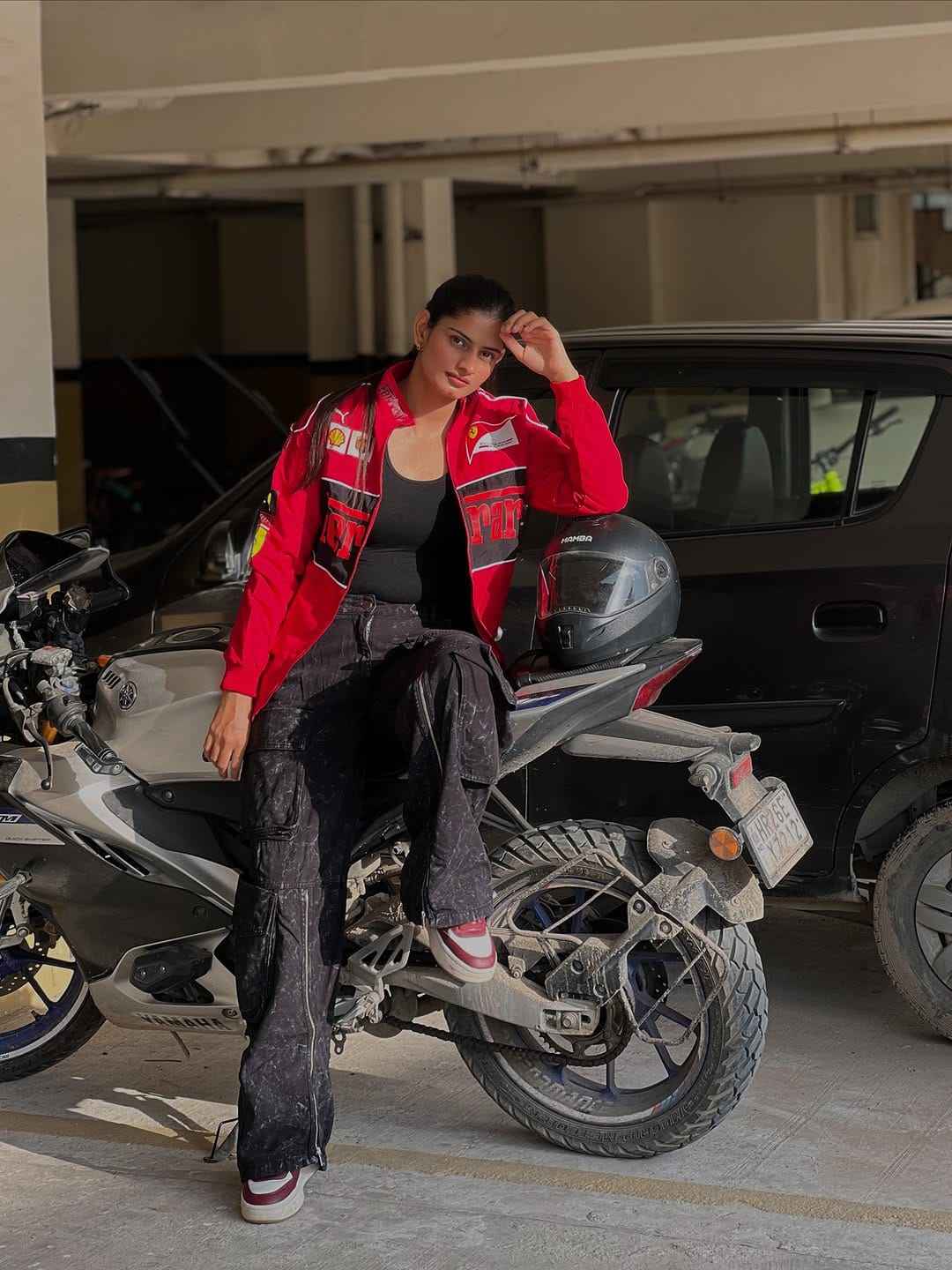 Ferrari Racing Jacket Red - Unleash Your Motorsport Spirit with Style, model wearing a red racing jacket while sitting on a motorcycle in a parking garage