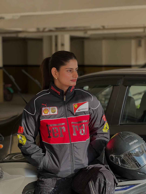 Black Ferrari Racing Jacket - Elevate Your Style and Showcase Your Passion worn by a woman beside a car and racing helmet by Xoratic