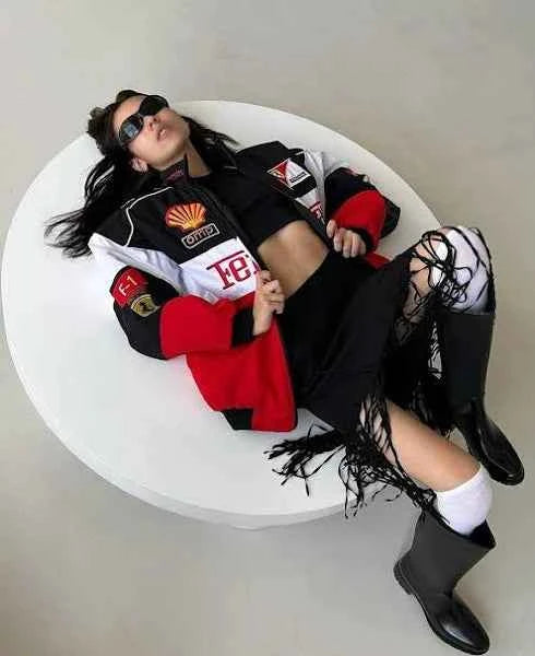 Ferrari Racing Jacket Tri-Colour: Elevate Your Style with Authentic Motorsport Flair, worn by a model in a black, red, and white racing jacket lounging in a chair